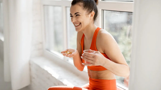 Frau in orange-farbener Sportkleidung, die glücklich das Nahrungsergänzungsmittel in der Hand hält