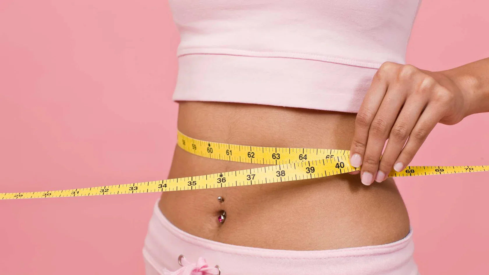 Weibliche Person misst mit einem Maßband den Bauchumfang