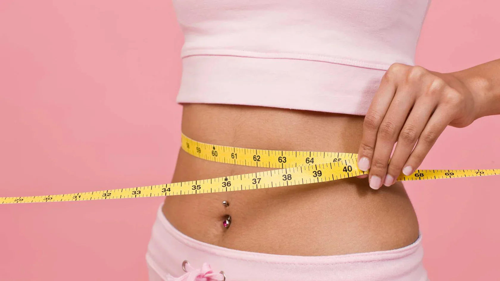 Weibliche Person misst mit einem Maßband den Bauchumfang 